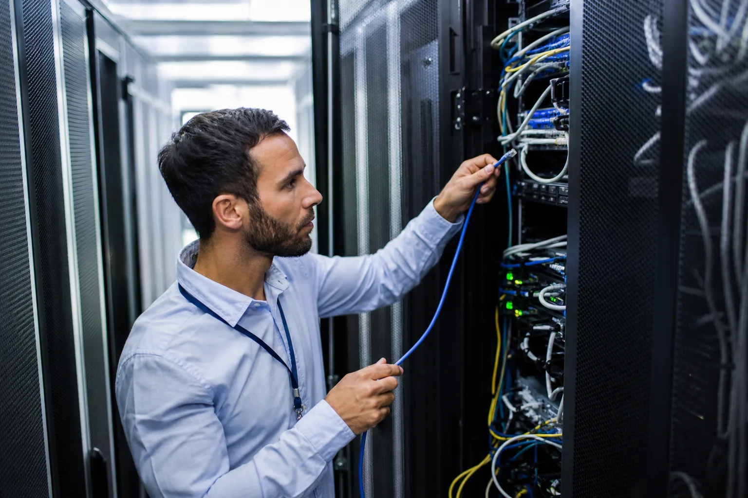 Un technicien branche un câble réseau sur une baie de serveurs dans une salle de data center
