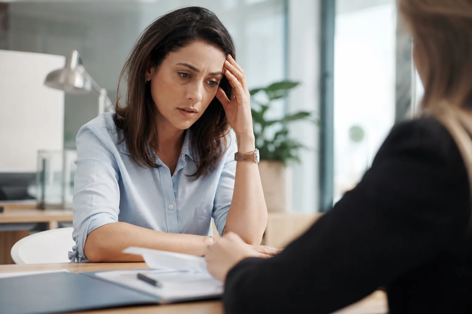 Personne inquiète consultant son application bancaire sur smartphone après un virement envoyé par erreur, à un bureau